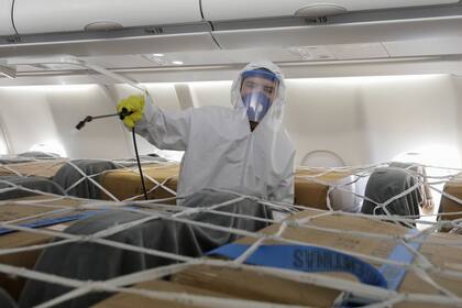 Un operario desinfecta la carga de un vuelo de Aerolíneas proveniente de China