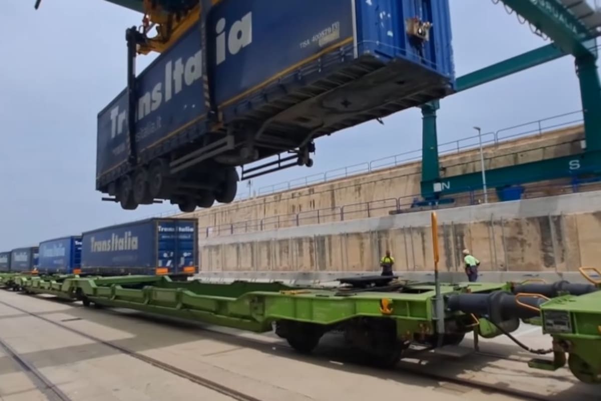 Un operario eleva un camión de Transitalia llegado al Puerto de Valencia y lo monta en un tren de la autopista ferroviaria con dirección a Madrid
