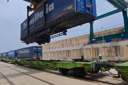 Un operario eleva un camión de Transitalia llegado al Puerto de Valencia y lo monta en un tren de la autopista ferroviaria con dirección a Madrid