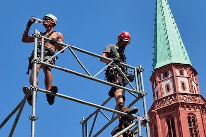 Un operario toma agua mientras instala un escenario para un triatlón Ironman, en Fráncfort, Alemania