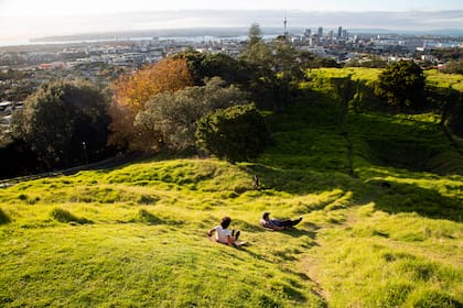Un padre y su hijo disfrutan sobre el pasto en una colina de Auckland, la ciudad más grande Nueva Zelanda