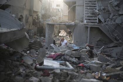 Un palestino habla por teléfono junto a edificios destruidos en un bombardeo israelí sobre la Franja de Gaza, en Rafah, el domingo 22 de octubre de 2023.