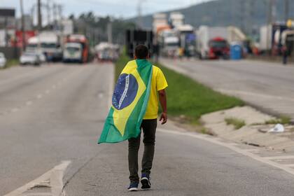 Un partidario del presidente Jair Bolsonaro con una bandera nacional brasileña sobre sus hombros en la región metropolitana de Florianópolis, estado de Santa Catarina, Brasil, el 31 de octubre de 2022