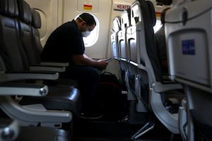 Un pasajero con barbijo mira su teléfono mientras espera a bordo de un avión de United Airlines antes de despegar del Aeropuerto Intercontinental George Bush el 11 de mayo de 2020 en Houston, Texas
