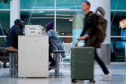 Un pasajero pasa frente a una caja de votos en el Aeropuerto Internacional de Charlotte-Douglas, el viernes 22 de noviembre de 2024, en Charlotte, Carolina del Norte. (AP Foto/Erik Verduzco)