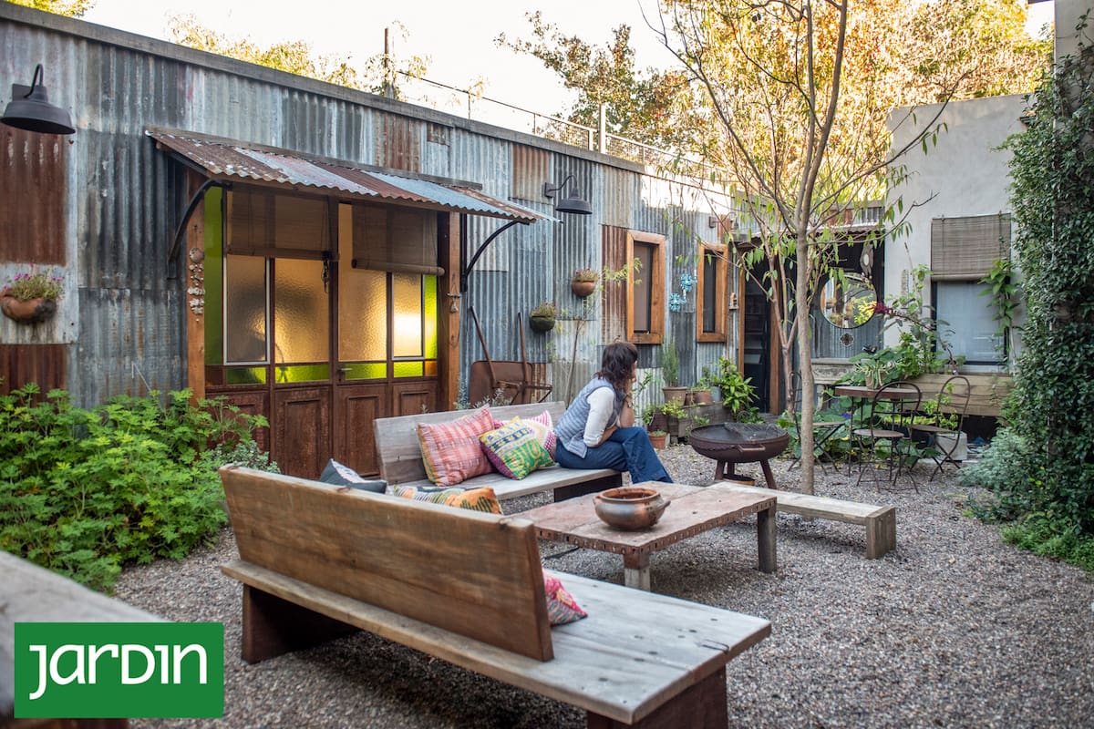 Un patio con living exterior conecta la casa con el estudio revestido en chapa oxidada