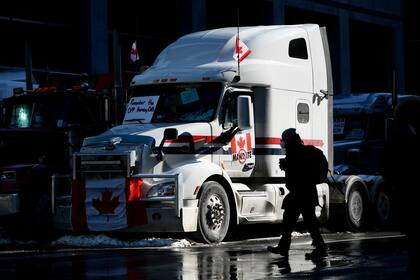 Un peatón cruza la calle cerca de un camión estacionado en la calle Metcalfe, el lunes 7 de febrero de 2022, durante las protestas contra las restricciones por el COVID-19, en Ottawa, Canadá. (Justin Tang/The Canadian Press vía AP)