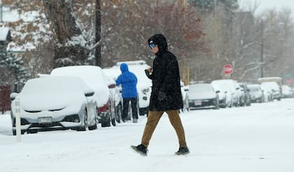 Un peatón cruza la Primera Avenida mientras una tormenta invernal azota Estados Unidos, desplomando las temperaturas y trayendo consigo una ligera nevada a su paso el sábado 18 de enero de 2025, en Denver