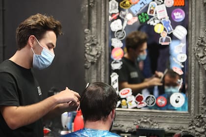 Un peluquero corta el pelo de un cliente en Cardiff, Gales del Sur, el 20 de octubre de 2020, antes de un breve cierre de dos semanas que comenzará el 23 de octubre, después de que los casos del nuevo coronavirus comenzaron a aumentar nuevamente