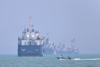 Un pequeño bote pasa frente a embarcaciones ancladas en el estrecho de Ormuz, frente a Bandar Abbas, Irán