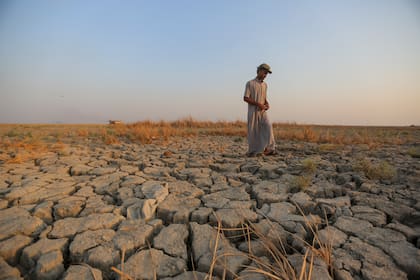 Un pescador camina por un terreno seco en las marismas de la provincia de Dhi Qar, Irak, 2 de septiembre de 2022. Tres años de sequía han afectado a millones de personas en Siria, Irak e Irán. (Foto AP/Anmar Khalil, Archivo)