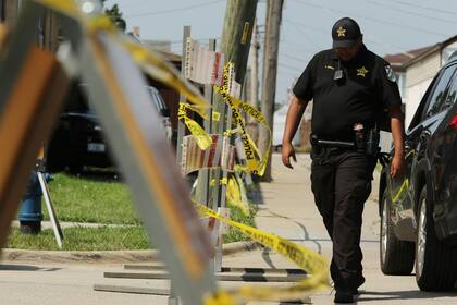 Un policía camina cerca de una casa donde se encontraron dos cadáveres en el patio, en un suburbio de Lyons, Chicago, el 28 de agosto de 2021. (Stacey Wescott/Chicago Tribune via AP)