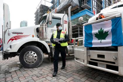 Un policía entrega órdenes de desalojo a manifestantes en Ottawa, Canadá, el 16 de febrero de 2022. La capital de Canadá lleva días paralizada debido a las protestas de personas que se oponen a las restricciones contra el coronavirus. (Adrian Wyld /The Canadian Press via AP)
