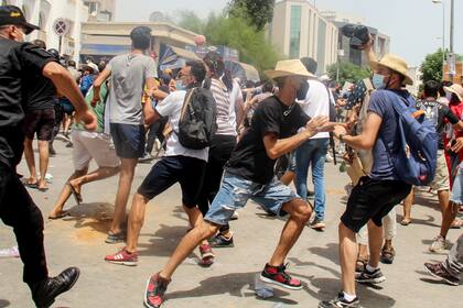 Un policía tunecino se enfrenta con manifestantes durante una protesta en Túnez, el domingo 25 de julio de 2021. (AP Foto/Hassene Dridi)