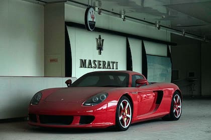 Un Porsche Carrera GT debajo de un cartel de la firma italiana Maserati