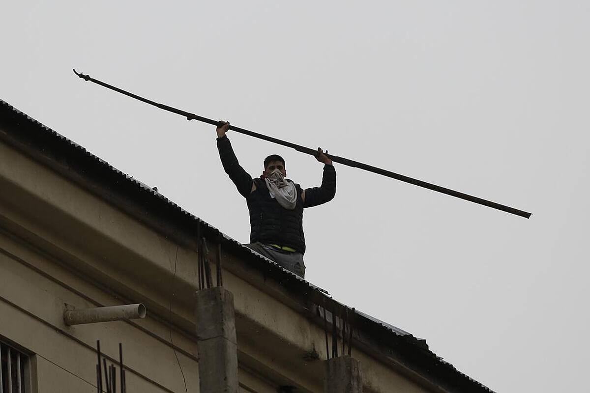 Un preso muestro un hierro desde los techos del penal