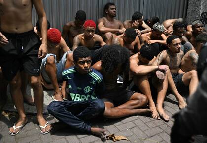 Un presunto delincuente arrestado durante la Operación Contención en la favela Vila Cruzeiro mira fijamente a un policía en el complejo Penha, Río de Janeiro