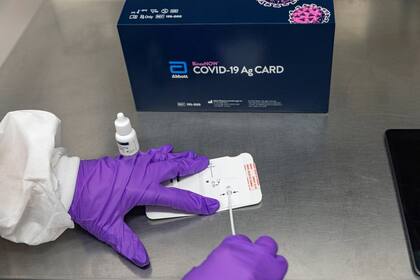 Un profesional de la salud añade el reactivo de extracción y una muestra del paciente a la tarjeta de prueba rápida BinaxNOW en una fotografía sin fecha publicada por Abbott Labs