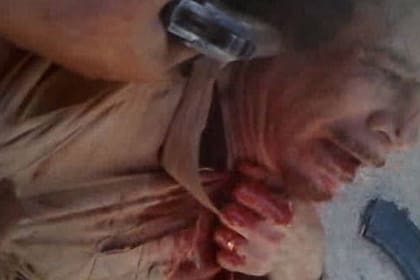 Un rebelde apoya un arma en la sien de un Muamar Gadafi ya vencido
