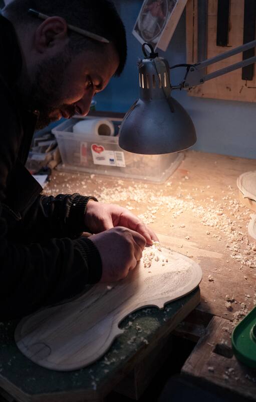 Un recluso trabaja con un trozo de madera procedente de un barco de inmigrantes para fabricar un violín como parte del proyecto 'Violines del mar' en la prisión de Opera, cerca de Milán, el 8 de febrero de 2024