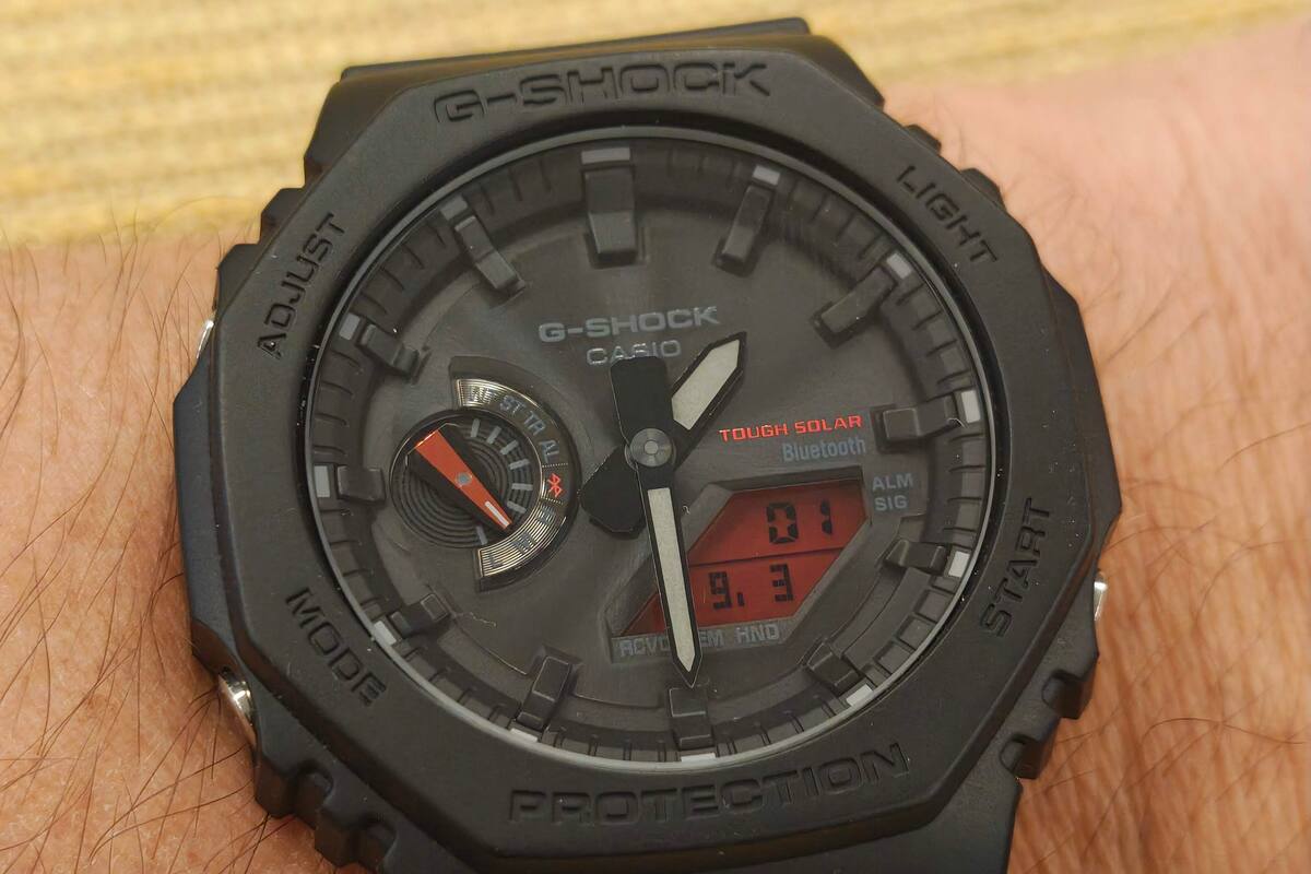 Un reloj Casio GA-B2100BBR-1A con cuadrante analógico, panel solar, conexión Bluetooth, y una pequeña pantalla LCD de fondo rojo