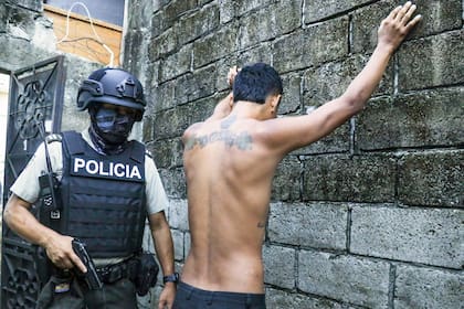 Un residente apoya las manos en un muro mientras la policía le registra para buscar armas o drogas, durante una operación contra grupos criminales en Guayaquil, Ecuador