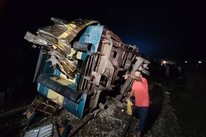 Un residente ayuda en las labores de rescate tras un choque entre un tren de mercancías y uno de pasajeros en Bhairab, en el distrito de Kishoreganj, Bangladesh, el 23 de octubre de 2023, que dejó más de una docena de muertos y decenas de heridos. (AP Foto/Mahmud Hossain Opu)
