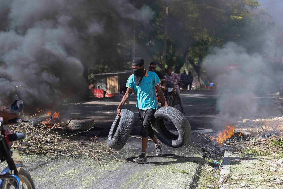 Un residente lleva neumáticos para colocarlos en una barricada en llamas para disuadir a los pandilleros de entrar a su vecindario, en Puerto Príncipe, Haití