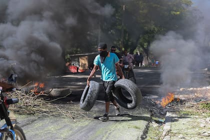 Un residente lleva neumáticos para colocarlos en una barricada en llamas para disuadir a los pandilleros de entrar a su vecindario, en Puerto Príncipe, Haití