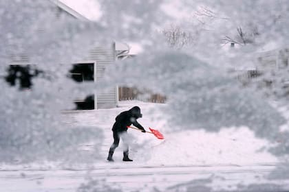 Un residente quita nieve con una pala al final de un camino de entrada, el jueves 22 de diciembre de 2022, en Urbandale, Iowa