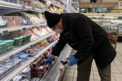 Un residente usa un barbijo y guantes mientras compra comida en un gran supermercado en en Codogno, una de las "zonas rojas" de Italia