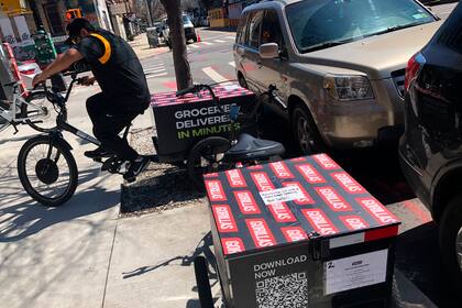 Un retartidor se prepara para hacer una entrega en bicicleta frente al minialmacén de la empresa Gorillas en la sección de Williamsburg del distrito neoyorquino de Brooklyn el lunes 12 de abril de 2022. (AP Foto/Tali Arbel)