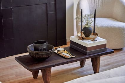 Un rincón del
living decorado con una mesa
ratona africana, libros de mesa,
velas, vasijas y una bandeja
dorada antigua de latón
