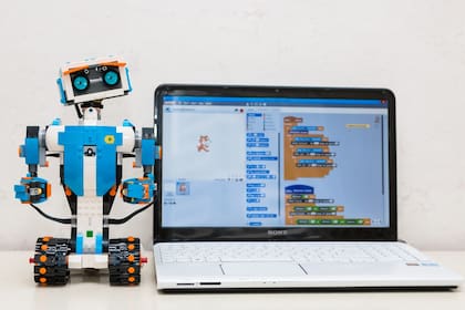 Un robot escolar de Lego y una pantalla con código en lenguaje Scratch