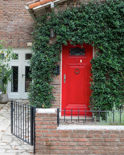 Un rojo potente apaciguado por el diseño clásico de la puerta y un jazmín tupido.