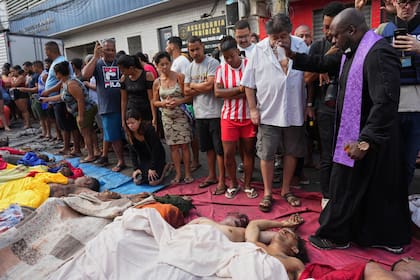 Un sacerdote bendice los cuerpos de personas asesinadas en la favela del Complexo da Penha, en Río de Janeiro, Brasil