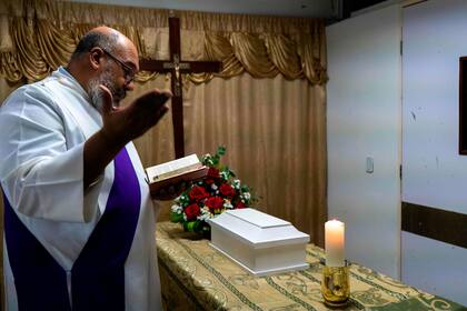 Un sacerdote católico oficia una misa durante el velorio del hijo de Wendy Dulcey, quien falleció un mes después de nacer en la unidad de cuidados intensivos del hospital Universitario de Caracas el 11 de enero de 2021