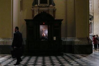 Un sacerdote con equipo de protección contra el coronavirus espera en el confesionario antes de una misa en la Basílica de San Juan de Letrán, en Roma, el viernes 30 de diciembre de 2022. (AP Foto/Alessandra Tarantino)
