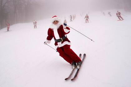 Un Santa Claus esquiando en el resort de esquí Sunday River en Newry, Maine el 10 de diciembre de 2023. (Foto AP/Robert F. Bukaty)