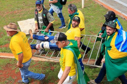 Un simpatizante del expresidente brasileño Jair Bolsonaro es asistido por otros simpatizantes después de ser herido durante enfrentamientos con la policía antidisturbios frente al Palacio Presidencial de Planalto en Brasilia