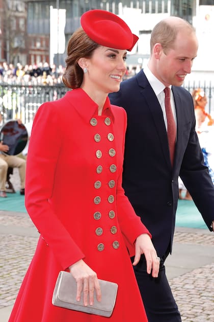 Un sobre color topo con detalles dorados con el que accesorizó el abrigo-vestido rojo, de Catherine Walker, para la misa del Día del Commonwealth.