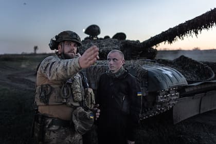 Un soldado al mando de la Brigada 22 de Ucrania da instrucciones frente a un tanque T-72 durante un ejercicio de tiro nocturno.