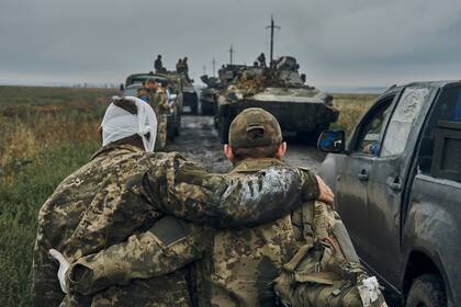 Un soldado ayuda a un compañero herido en la carretera en el territorio liberado por Ucrania en la región de Járkiv