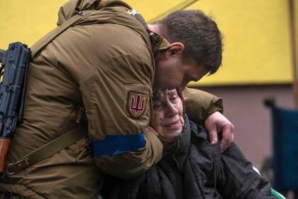 Un soldado consuela a Larysa Kolesnyk, de 82 años, después de que fuera evacuada de Irpín, a las afueras de Kiev, Ucrania, el miércoles 30 de marzo de 2022. (AP Foto/Rodrigo Abd)