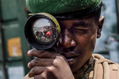 Un soldado del grupo rebelde M23 observa a través de una mira militar recuperada entre objetos militares abandonados en el puerto de Goma, el 18 de febrero de 2025