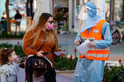Un soldado del Home Front Command de Israel guía a una residente para encontrar una carpa de prueba de Covid-19 en la ciudad turística central de Netanya el 7 de febrero de 2021, luego del levantamiento de un cierre nacional debido a la pandemia