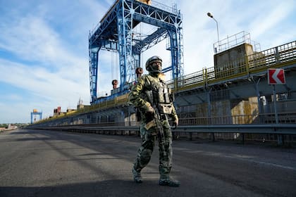 Un soldado ruso patrulla una zona de la central hidroeléctrica de Kakhovka, una planta de energía de funcionamiento en el río Dniéper en la región de Kherson, al sur de Ucrania, el 20 de mayo de 2022.