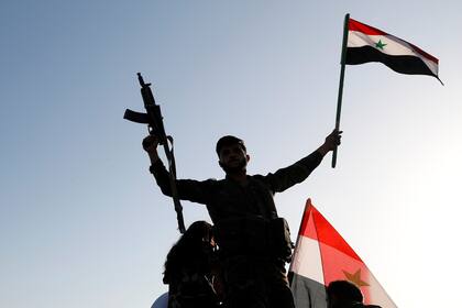 Un soldado sirio agita la bandera en una protesta contra los ataques aéreos en Damasco