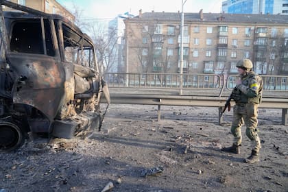 Un soldado ucraniano camina frente a un vehículo militar quemado, el sábado 26 de febrero de 2022, en Kiev, Ucrania. (AP Foto/Efrem Lukatsky)