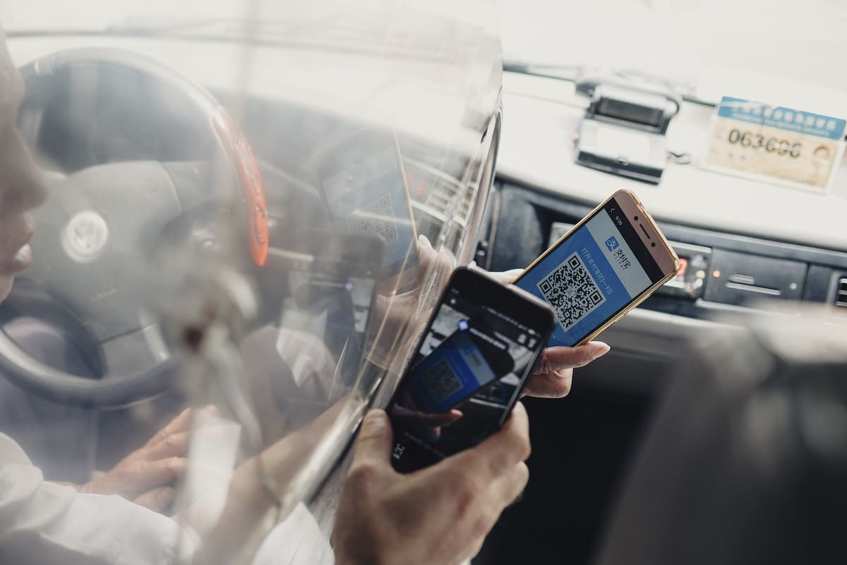 Un taxista sostiene un teléfono con un código QR para recibir el pago de un viaje
